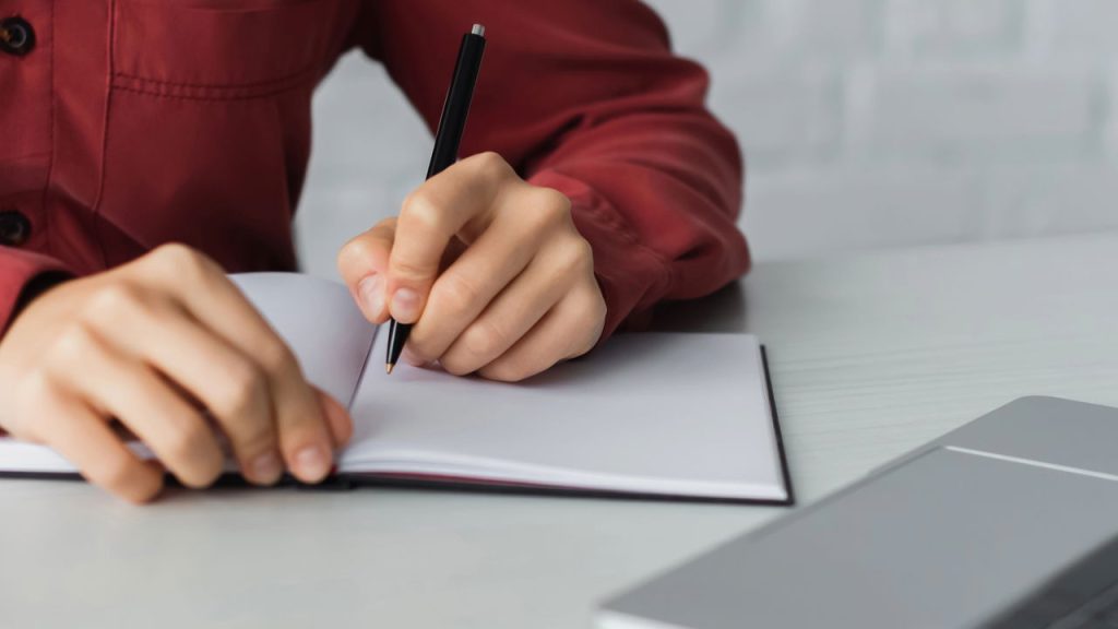 Estudante escrevendo em caderno