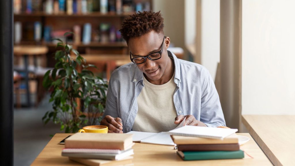 Estudante lendo e escrevendo em biblioteca